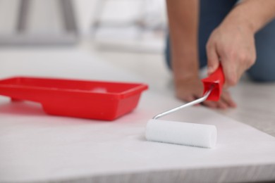 Man applying glue onto wallpaper sheet in room, closeup