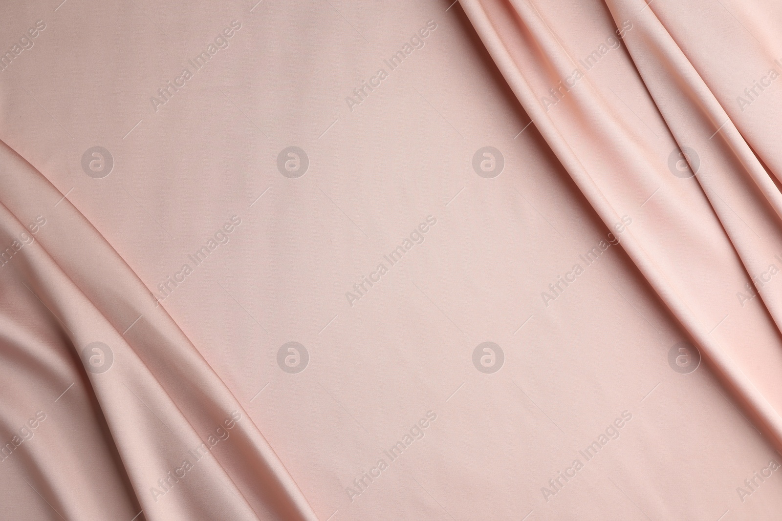 Photo of Crumpled pink silk fabric as background, top view. Space for text