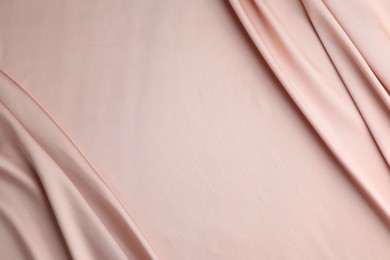 Photo of Crumpled pink silk fabric as background, top view. Space for text