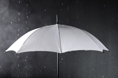 Photo of White umbrella under rain on dark background