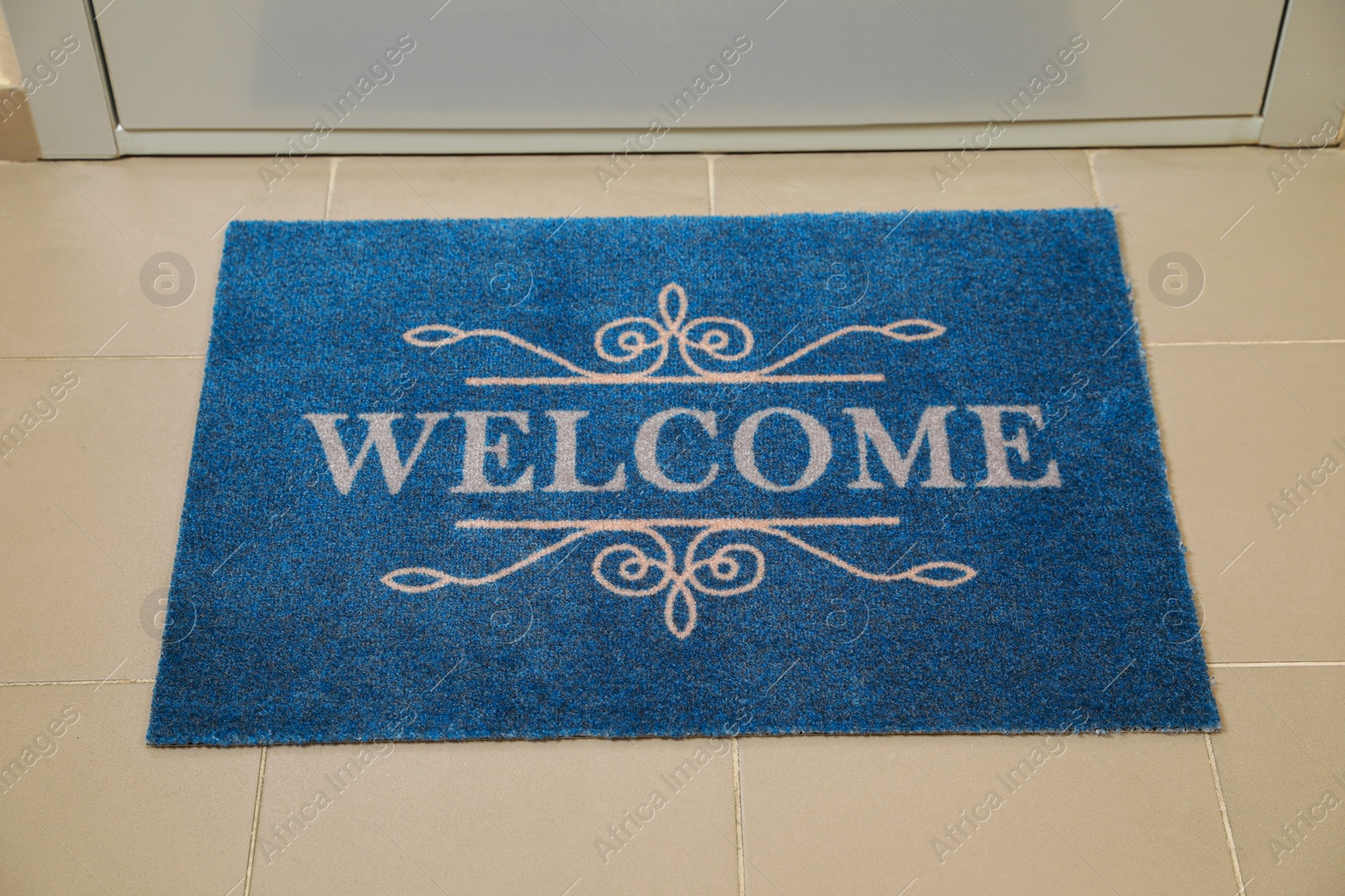 Photo of Beautiful blue doormat with word Welcome on floor near entrance