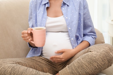 Photo of Pregnant woman drinking tea at home, closeup