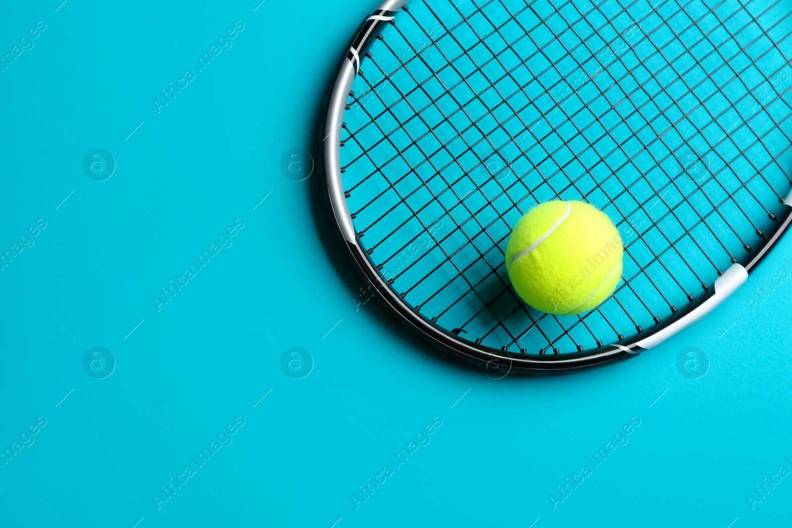 Photo of Tennis racket and ball on blue background, top view. Space for text