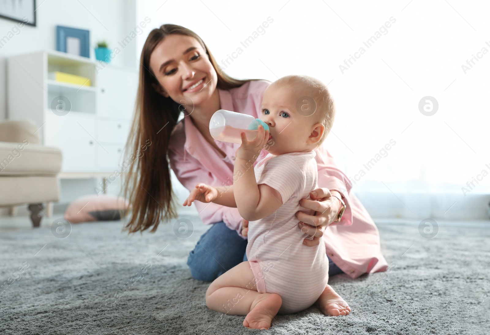 Photo of Happy mother with little baby on floor indoors