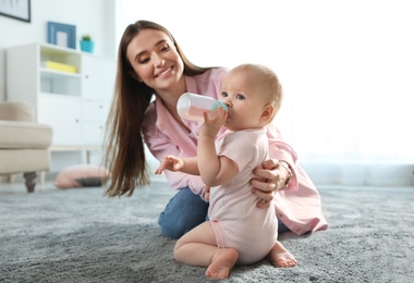 Photo of Happy mother with little baby on floor indoors