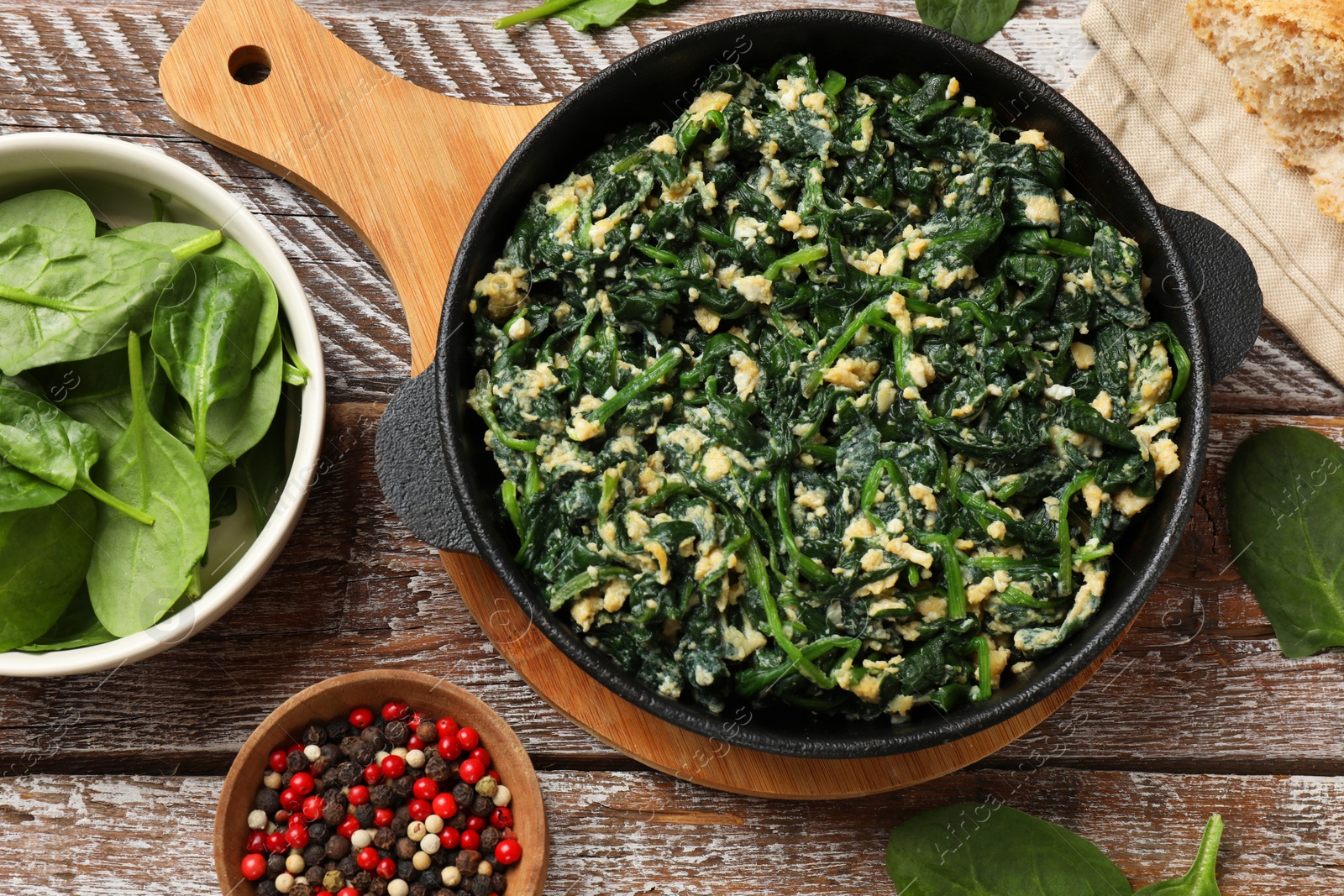 Photo of Tasty spinach dip with eggs in dish served on wooden table, flat lay