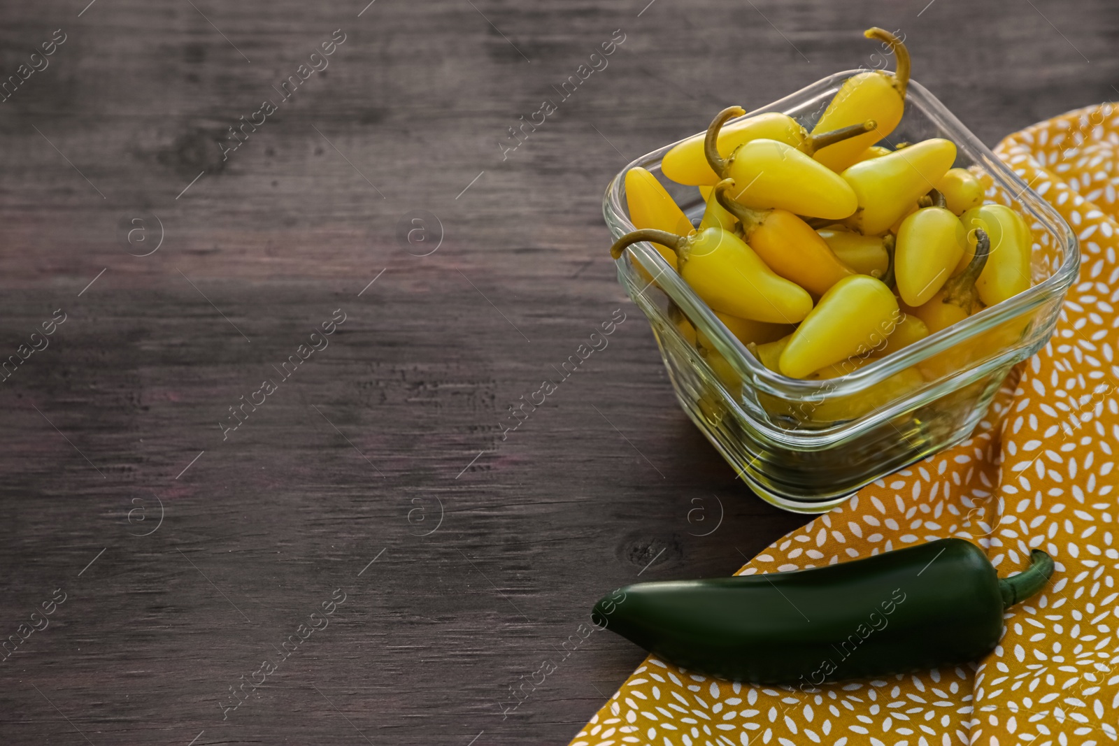 Photo of Fresh and pickled jalapeno peppers on wooden table. Space for text