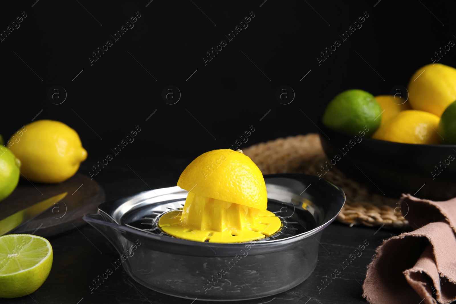 Photo of Squeezer, fresh lemons and limes on black table