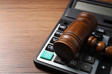 Photo of Tax law. Gavel and calculator on wooden table, closeup. Space for text
