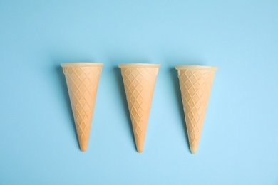 Photo of Empty wafer ice cream cones on blue background, flat lay
