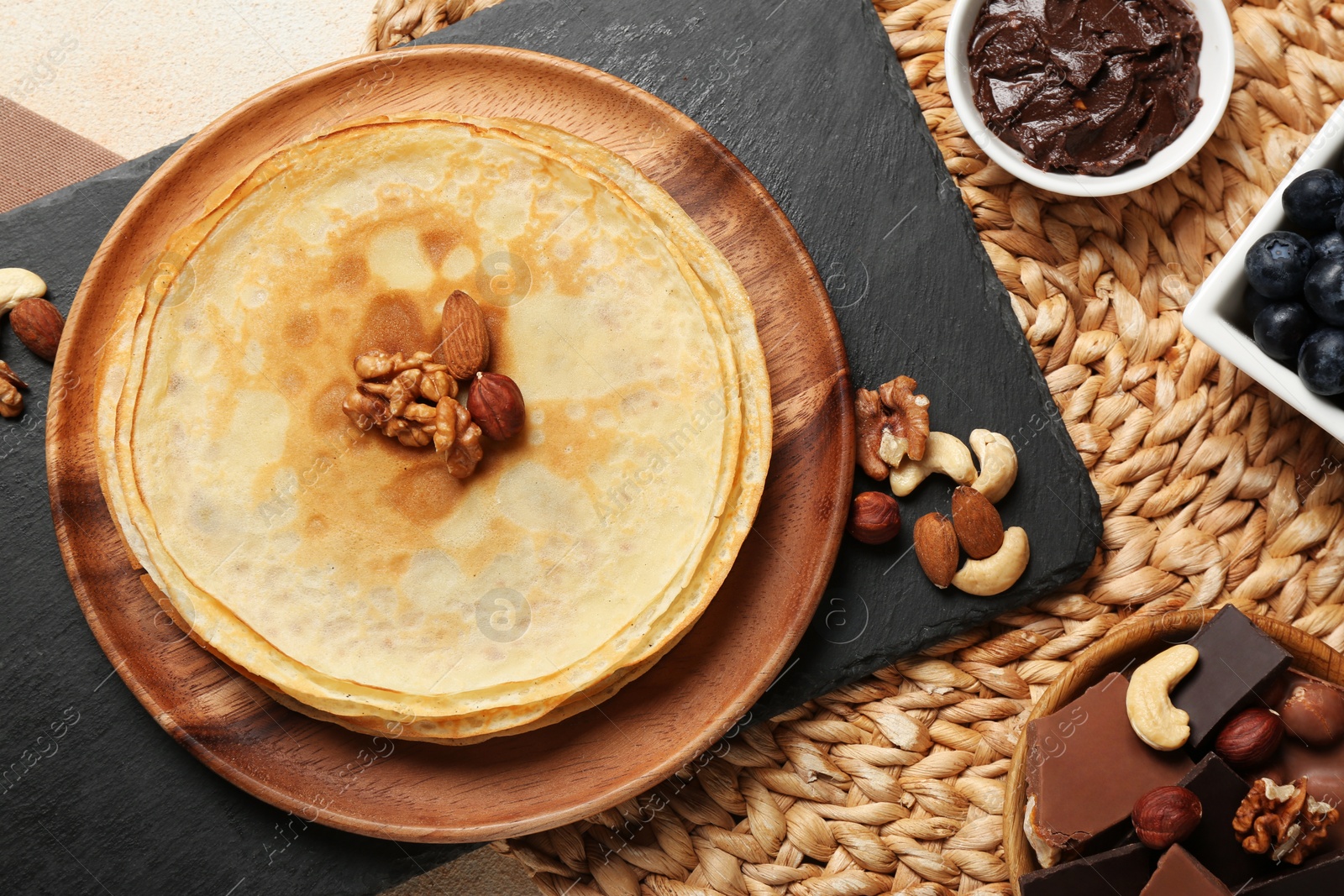 Photo of Delicious crepes with nuts and chocolate on table, flat lay