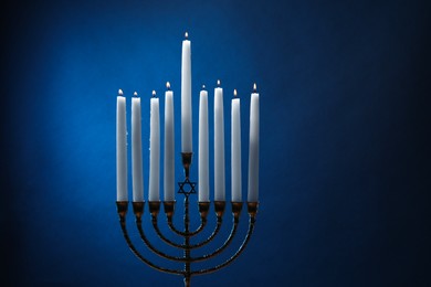 Hanukkah celebration. Menorah with burning candles on blue background