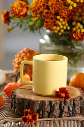 Cup of drink and autumn flowers on wicker table