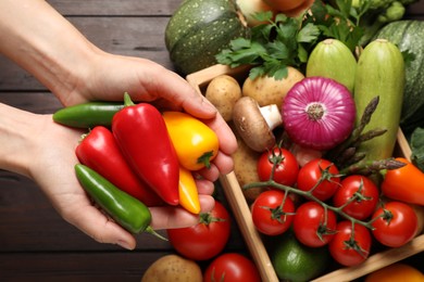 Photo of Man holding fresh vegetables at wooden table, closeup