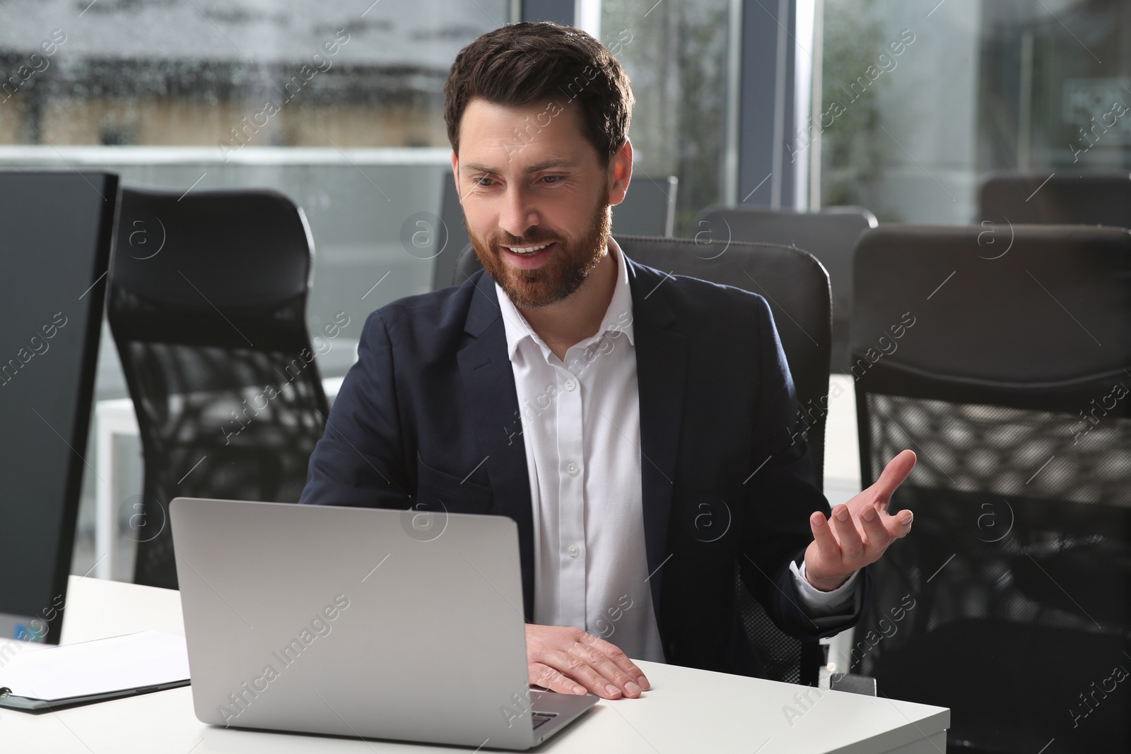 Photo of Man working on laptop at white desk in office