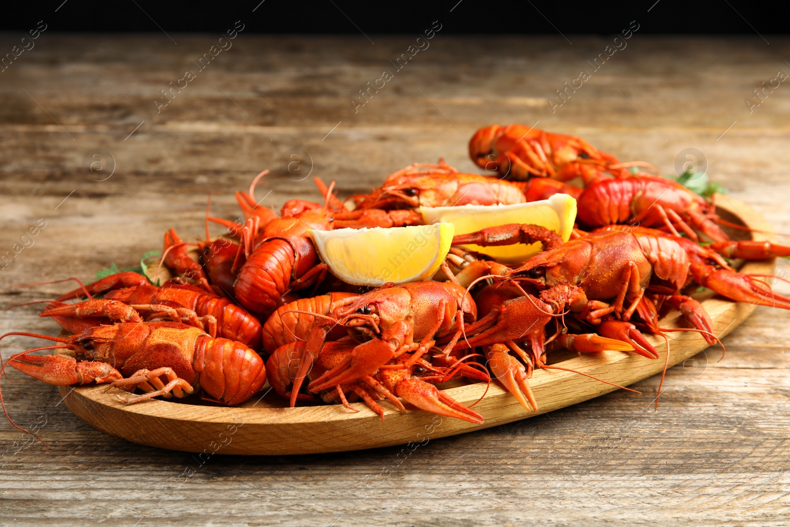 Photo of Tray of delicious boiled crayfishes on wooden table