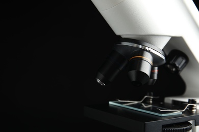 Photo of Closeup view of modern microscope on black background, space for text. Medical equipment