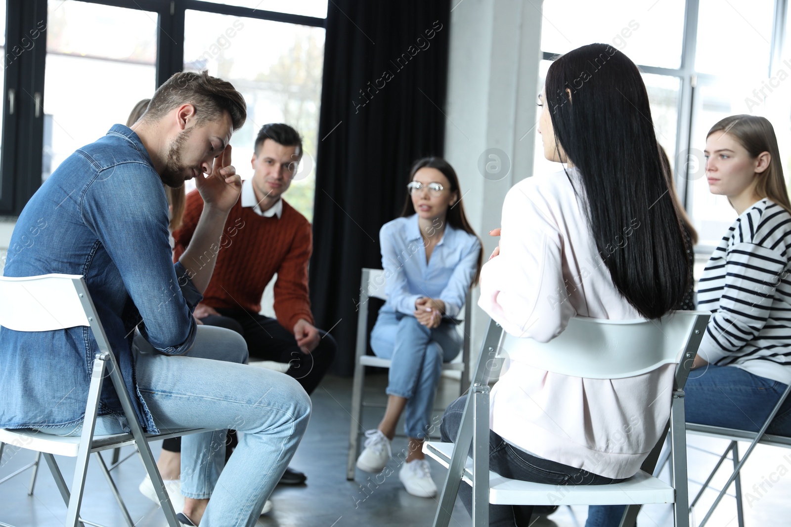 Photo of Psychotherapist working with patients in group therapy session indoors