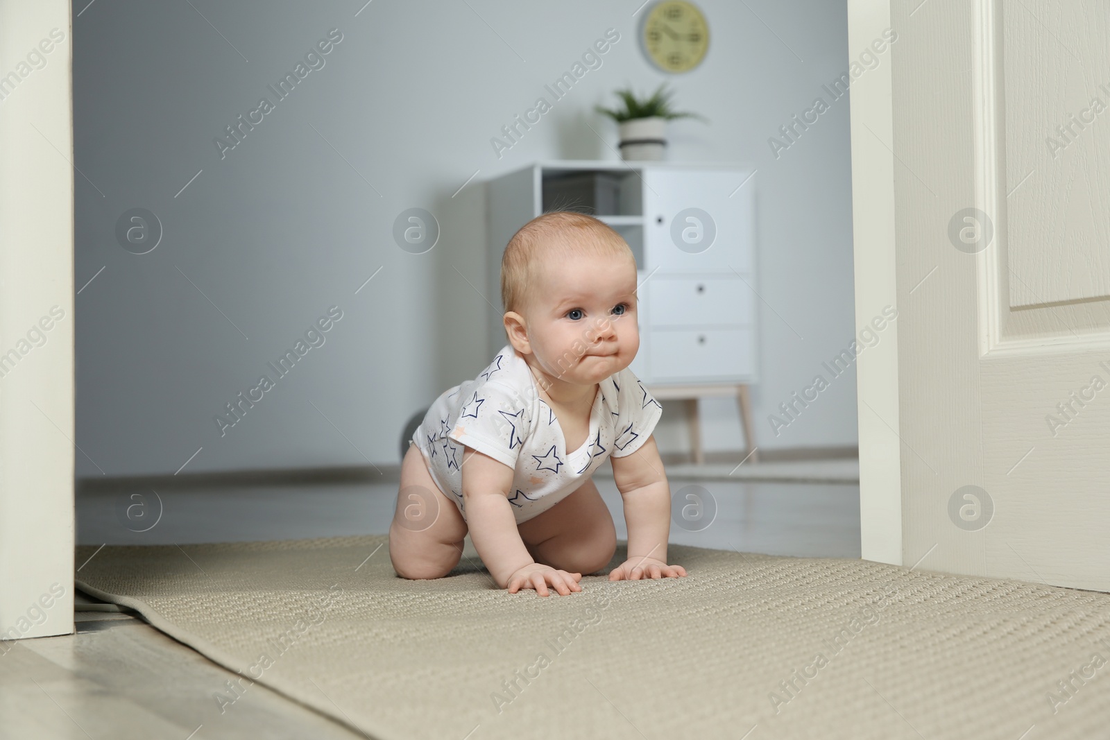 Photo of Cute little baby crawling on carpet indoors