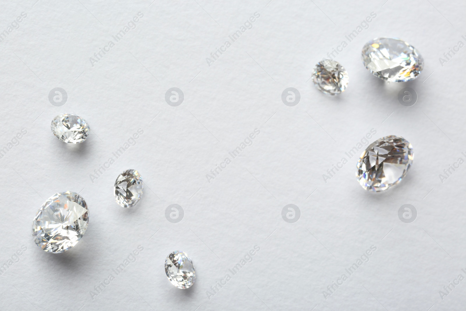 Photo of Many beautiful shiny diamonds on white background, flat lay. Space for text