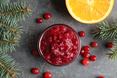 Photo of Flat lay composition with bowl of cranberry sauce and fir branches on grey background