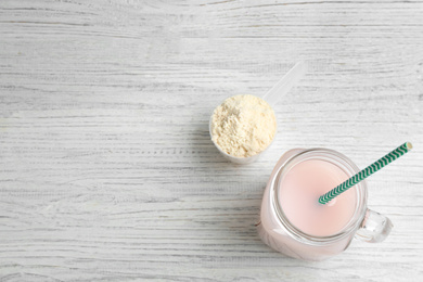 Protein shake and powder on white wooden table, flat lay. Space for text