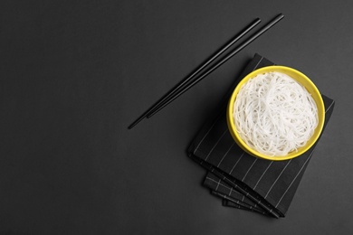 Cooked rice noodles served on black table, flat lay. Space for text