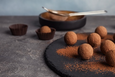 Photo of Slate plate with chocolate truffles on table, space for text