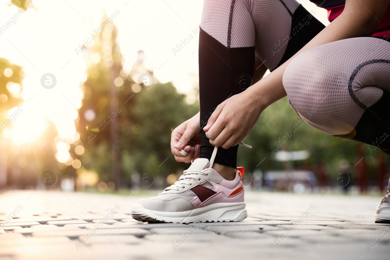 Photo of Woman tying shoelaces before morning run in park, closeup. Space for text