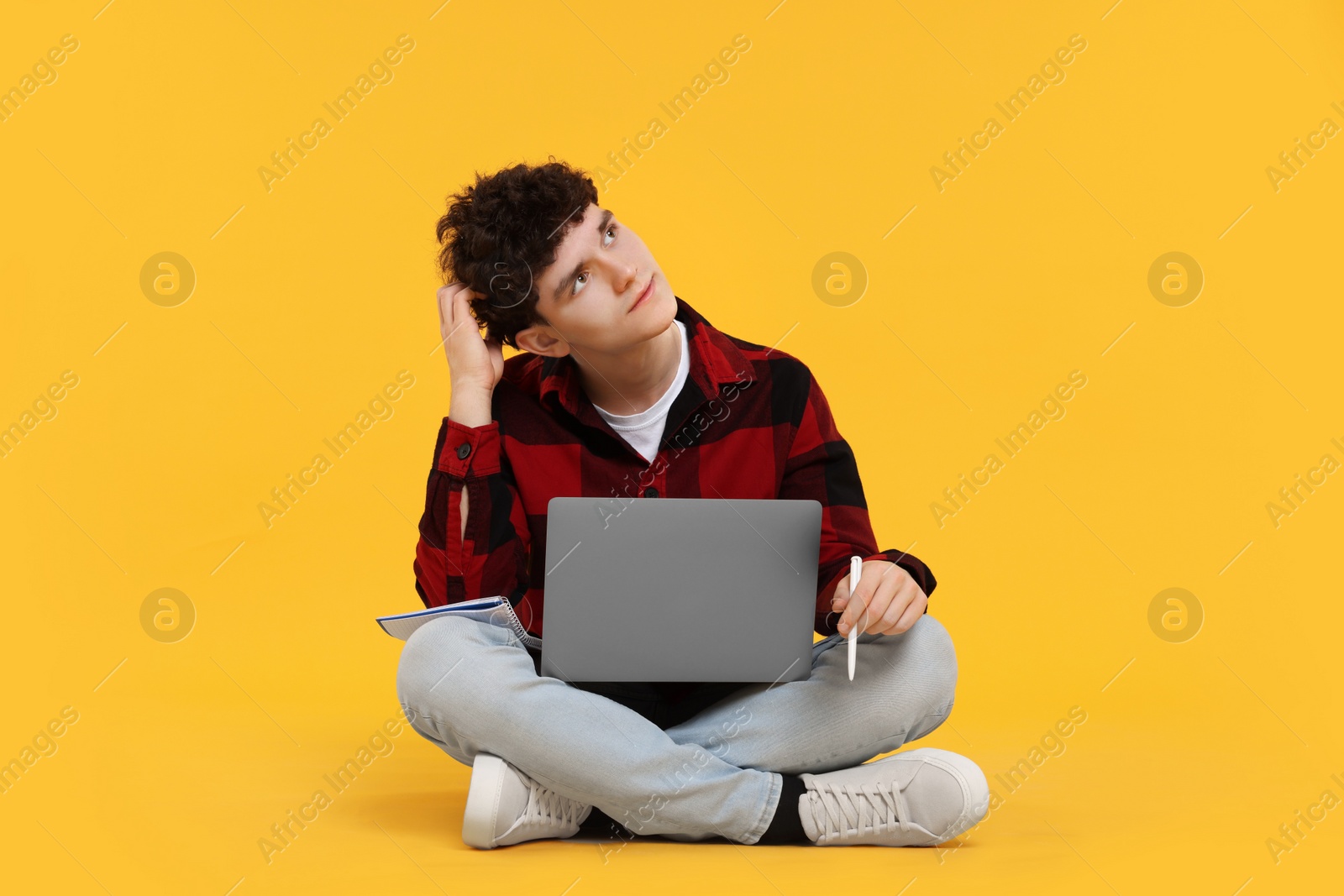 Photo of Portrait of student with laptop and pen on orange background