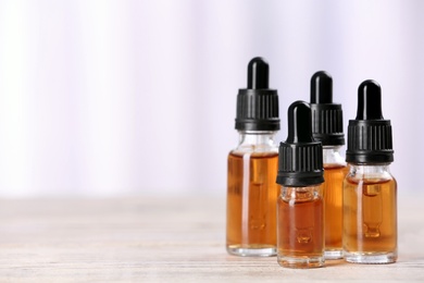 Bottles of essential oils on table against light background, space for text. Cosmetic products