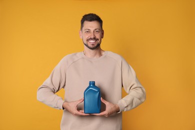 Photo of Man holding blue container of motor oil on orange background