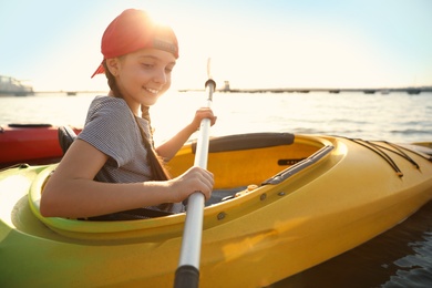 Happy little girl kayaking on river. Summer camp activity