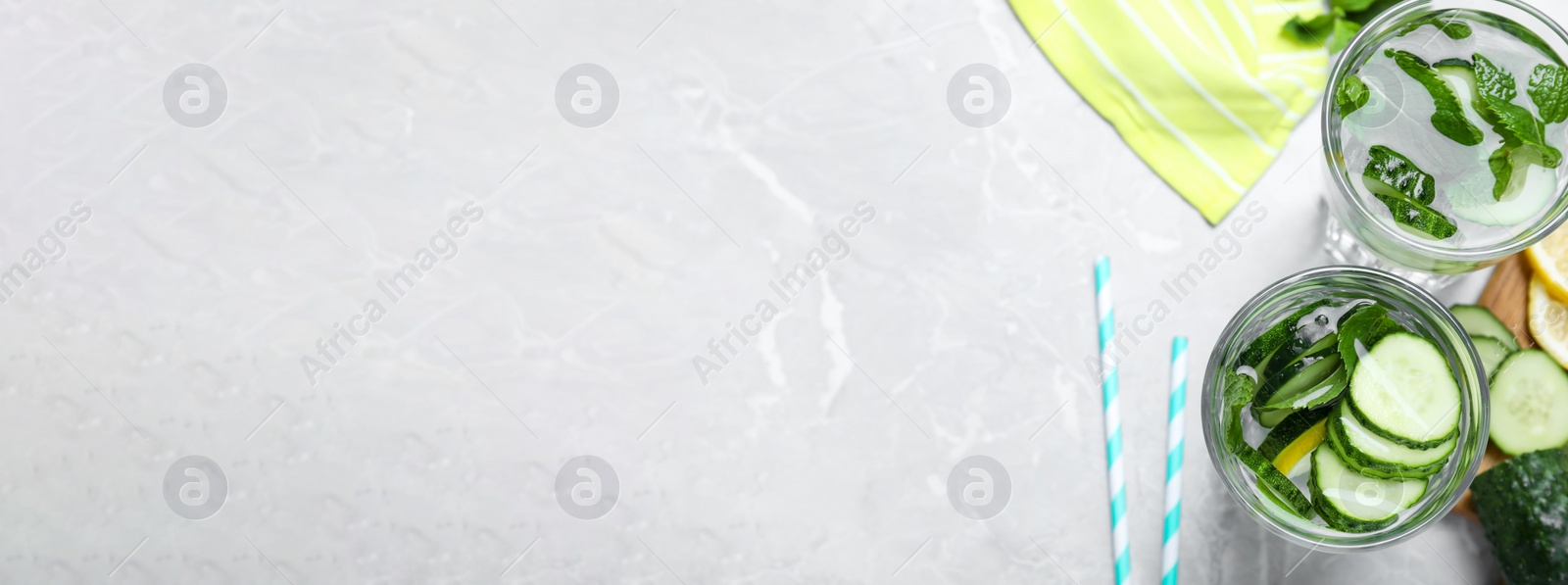 Image of Refreshing water with cucumber, lemon and mint on light grey table, flat lay with space for text. Banner design