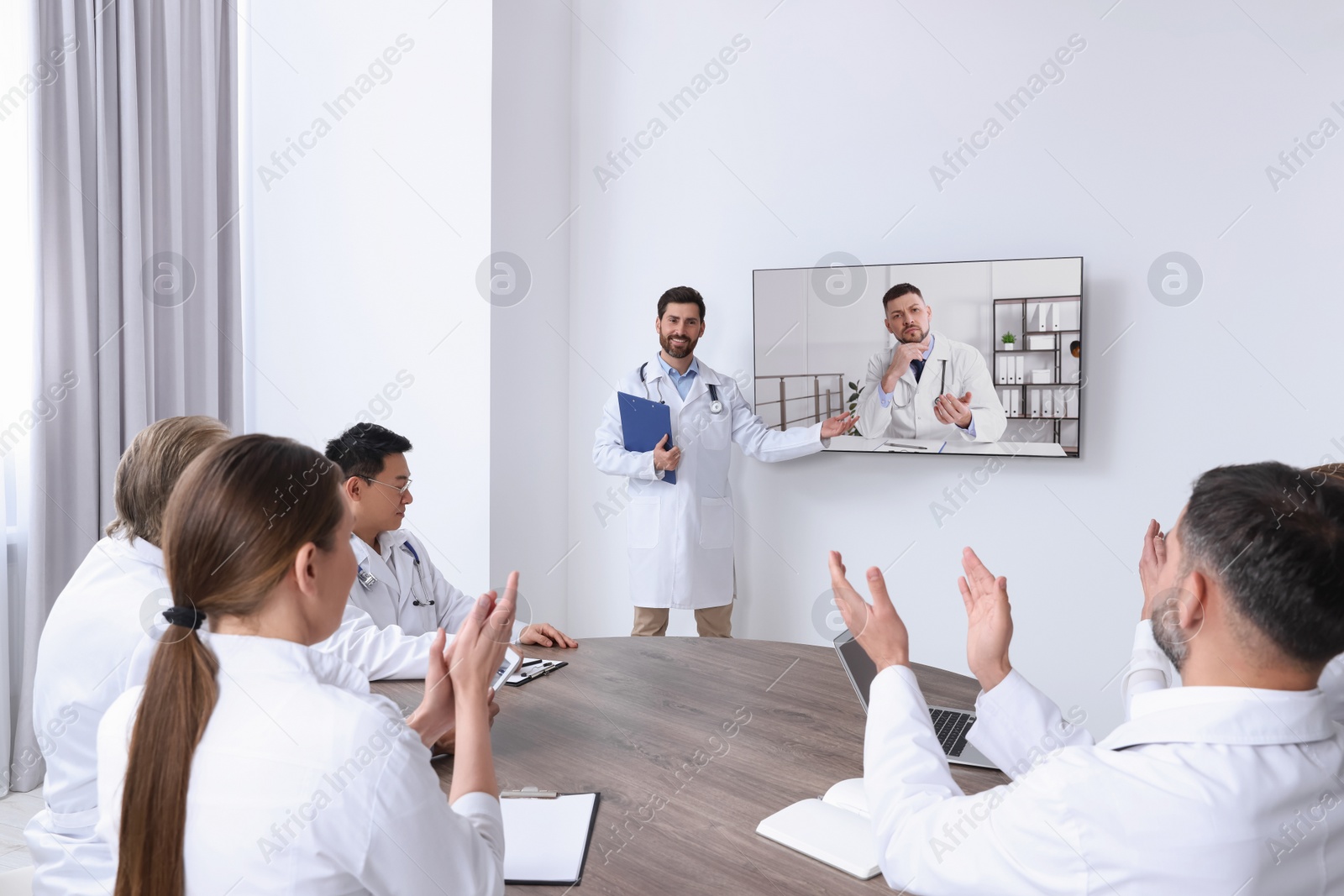 Image of Lecture with online participant. Doctors in meeting room. Using tv for videoconference