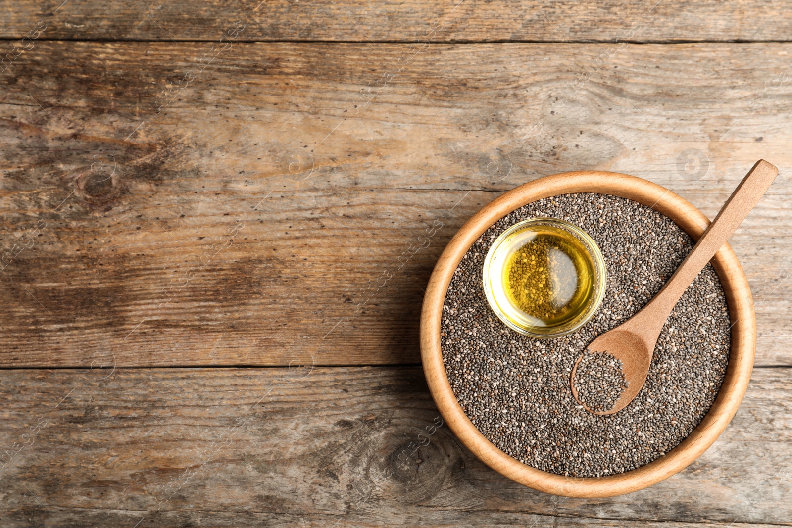 Photo of Bowl with chia seeds, oil and spoon on wooden table, top view. Space for text