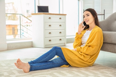 Attractive young woman talking on mobile phone near sofa