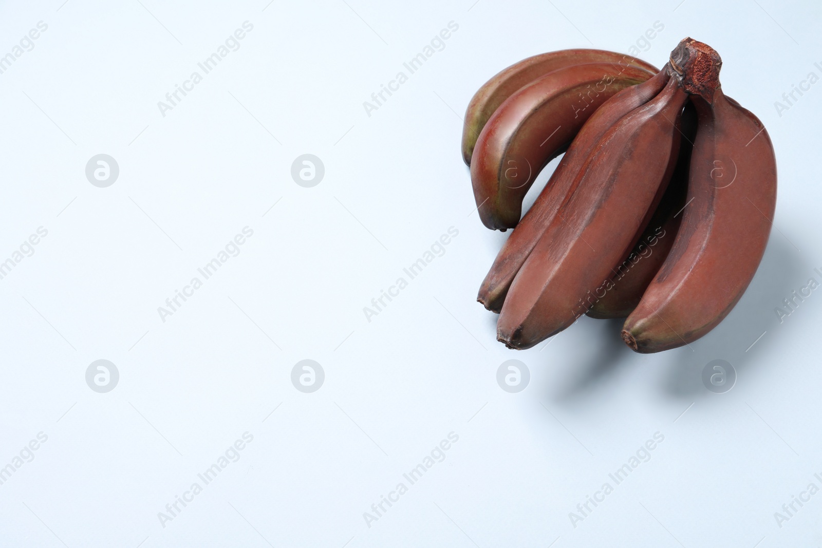 Photo of Tasty red baby bananas on light background, top view. Space for text