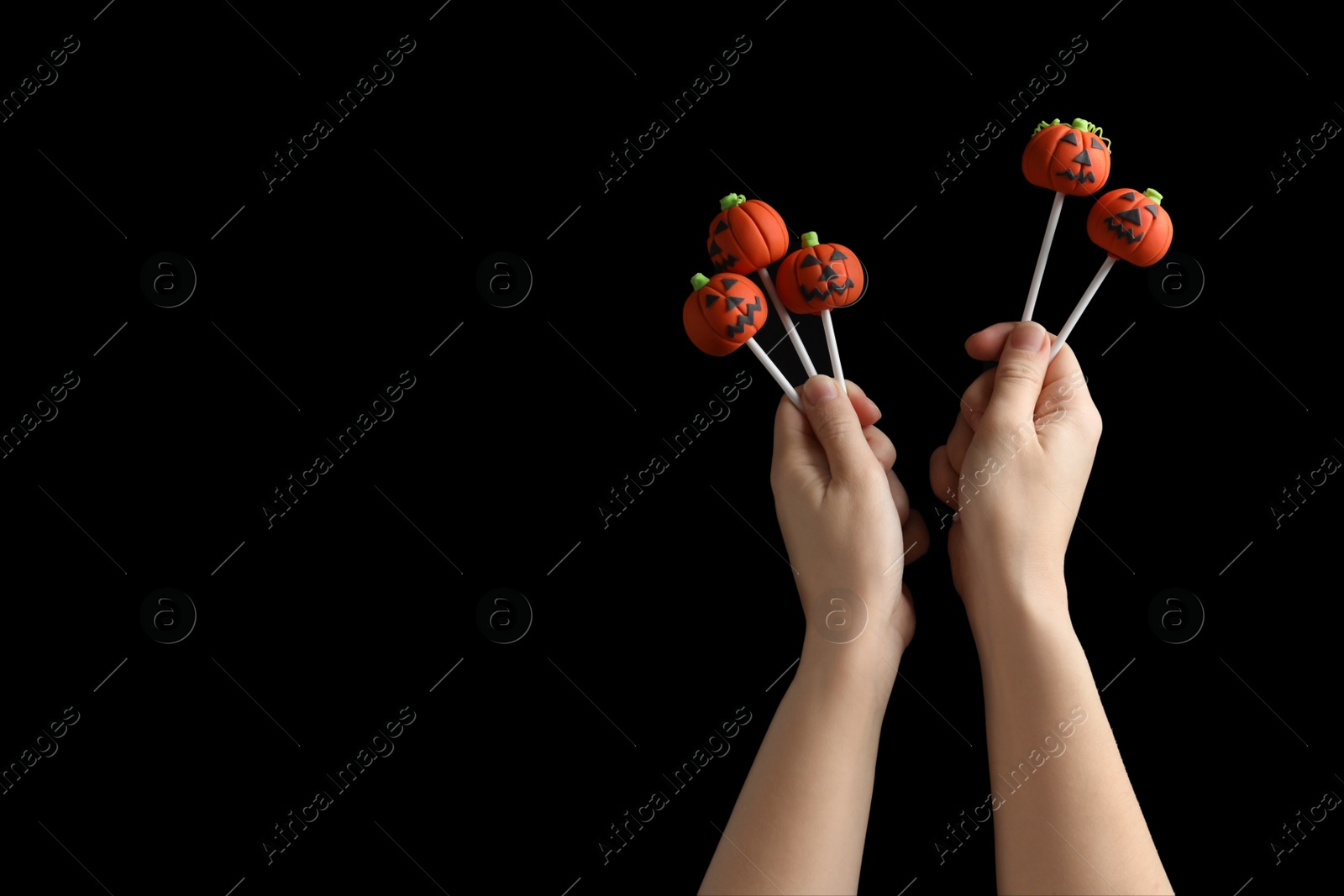 Photo of Woman with delicious pumpkin shaped cake pops and space for text on black background, closeup. Halloween celebration