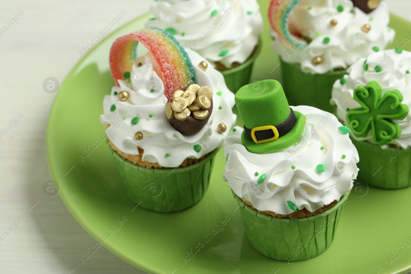 Photo of St. Patrick's day party. Tasty festively decorated cupcakes on white table, closeup