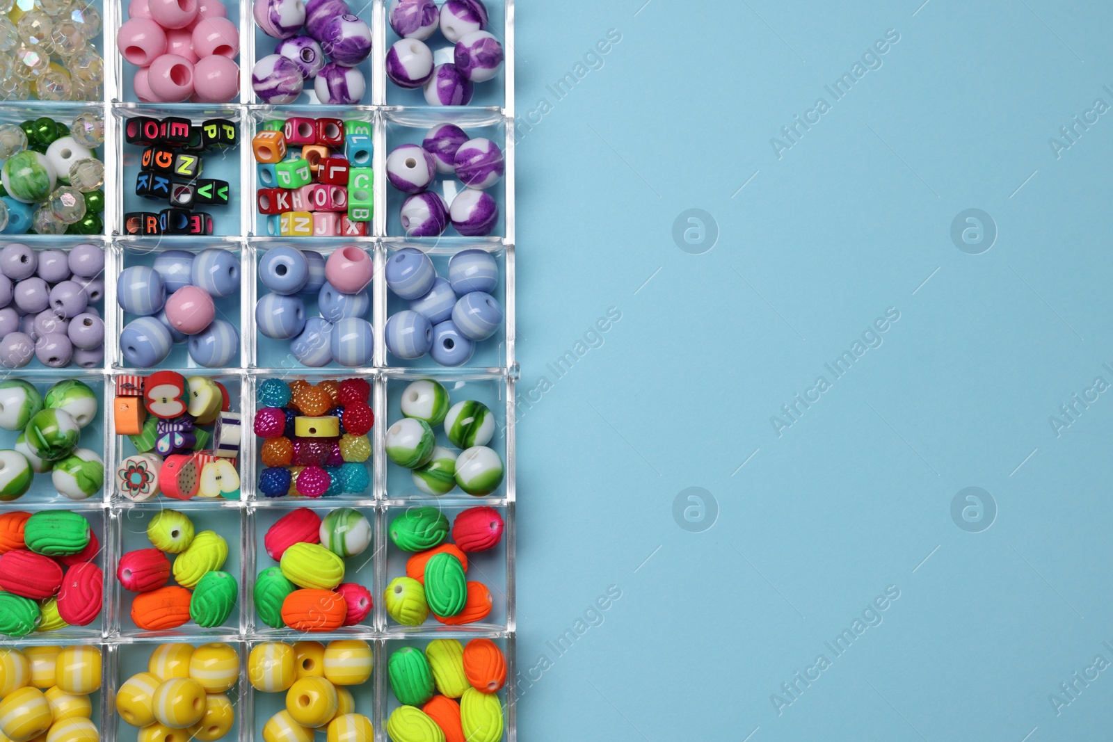 Photo of Box with different colorful beads on light blue background, top view. Space for text