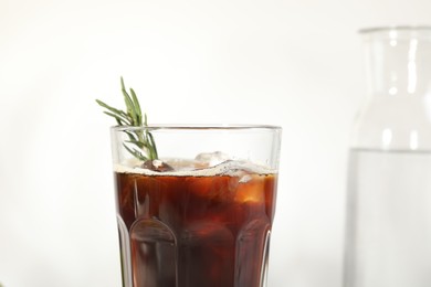 Photo of Refreshing iced coffee with rosemary in glass on white background, closeup