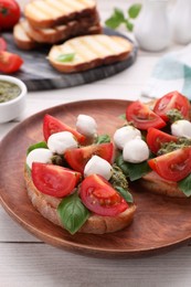 Delicious Caprese sandwiches with mozzarella, tomatoes, basil and pesto sauce on white wooden table, closeup