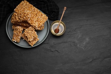Photo of Plate with puffed rice bars (kozinaki) on black table, above view. Space for text