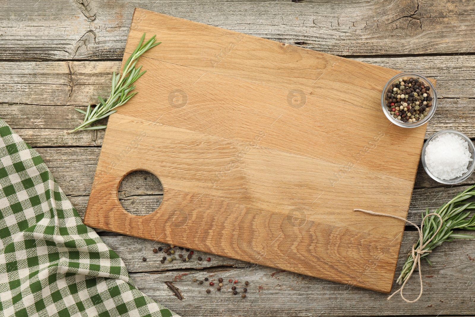 Photo of Cutting board, rosemary, salt and pepper on wooden table, flat lay. Space for text