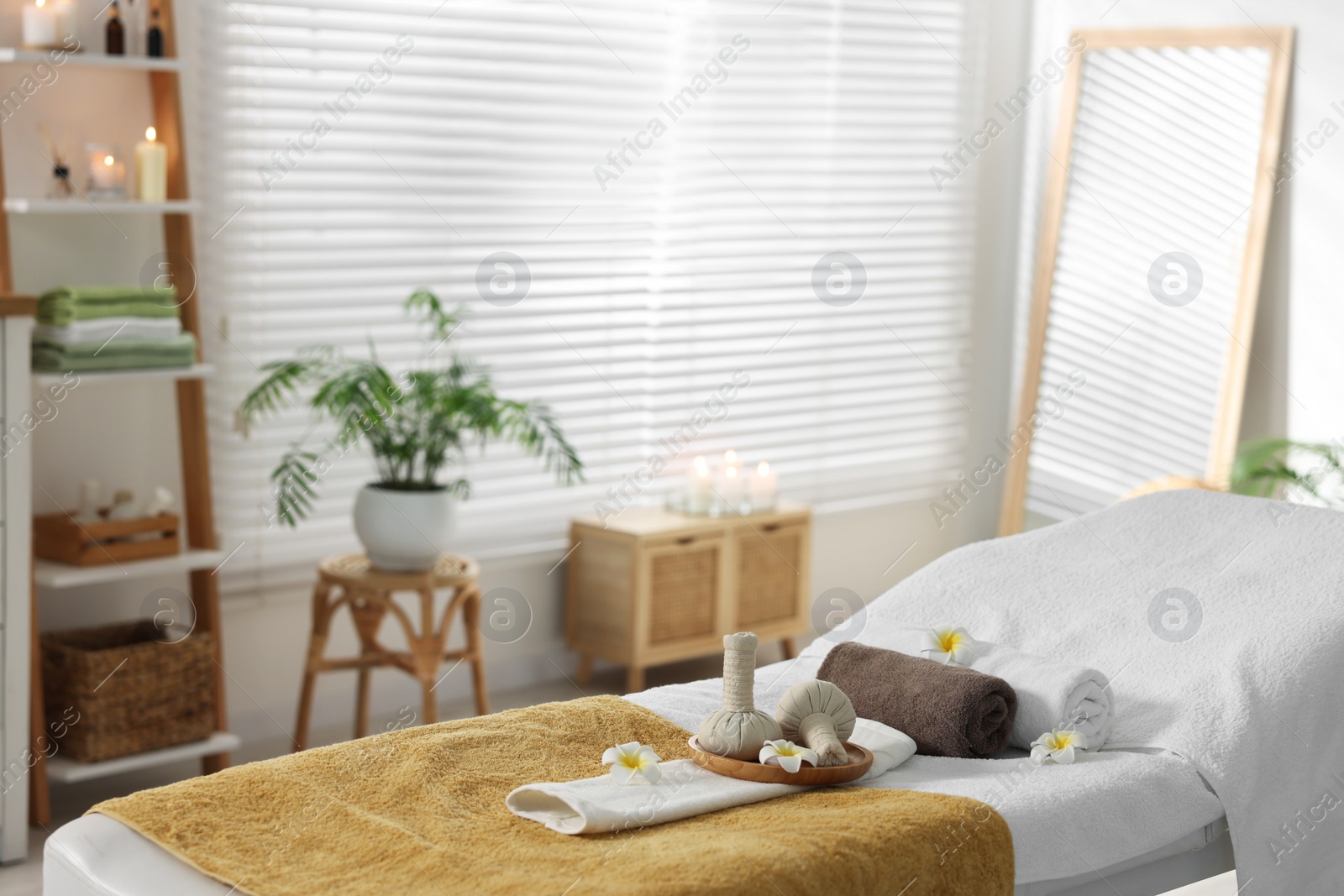 Photo of Herbal bags, flowers and towels on massage table in spa center