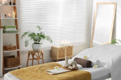 Herbal bags, flowers and towels on massage table in spa center