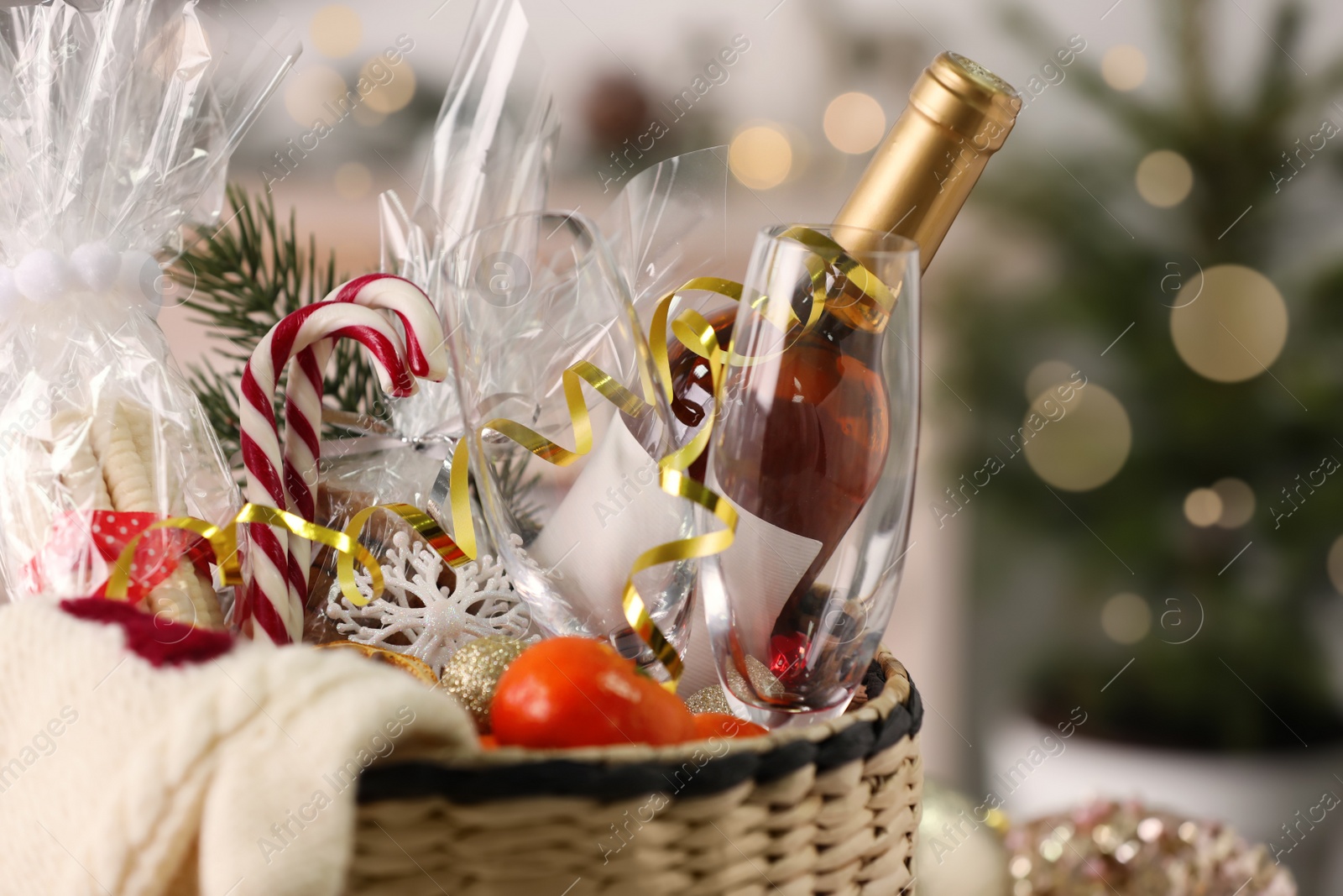 Photo of Wicker basket with Christmas gift set on blurred background, closeup