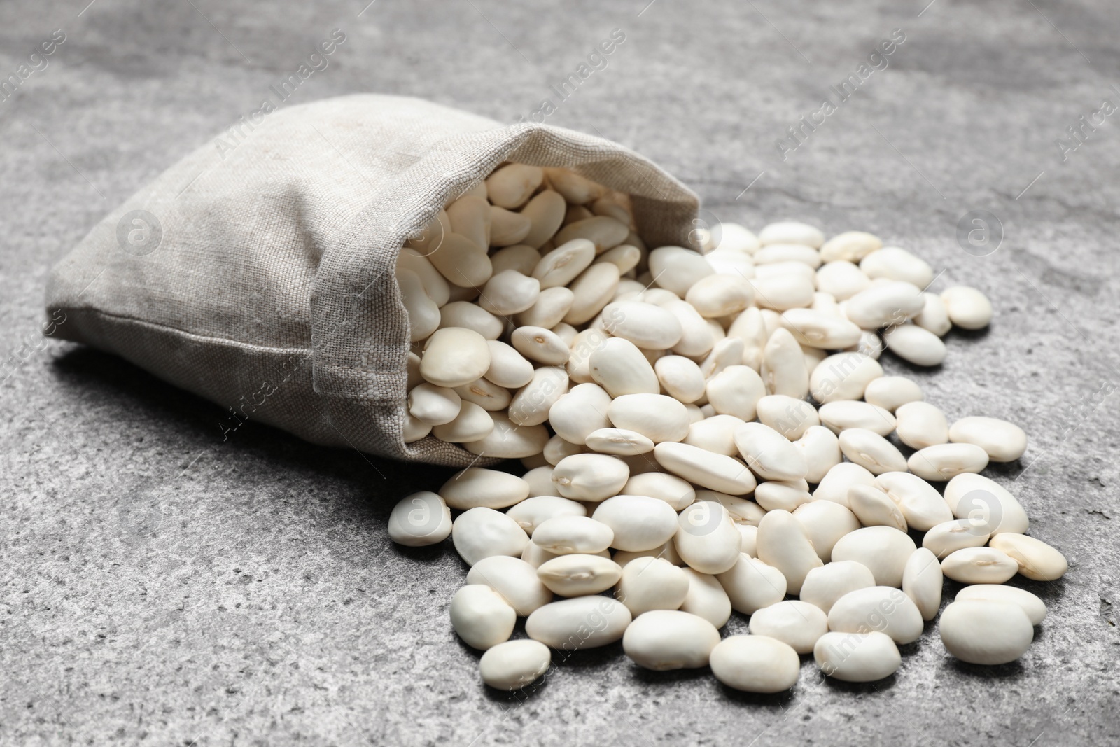 Photo of Bag with raw white beans on grey table