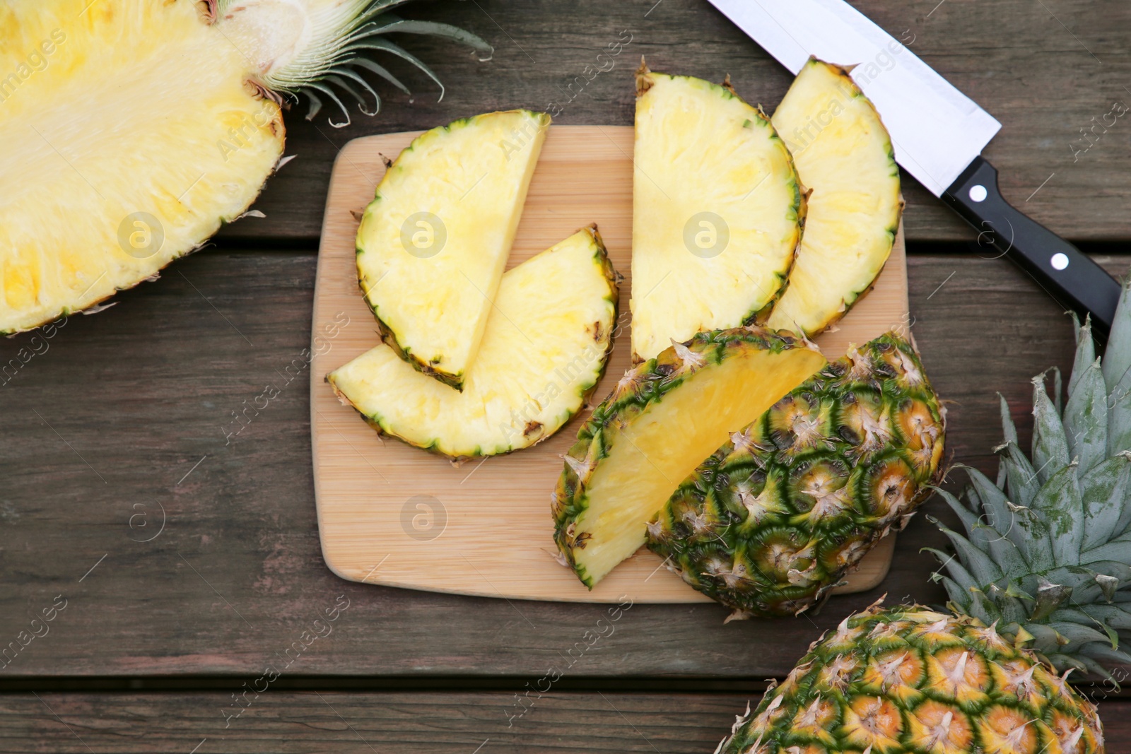 Photo of Cut and whole ripe pineapples on wooden table, flat lay